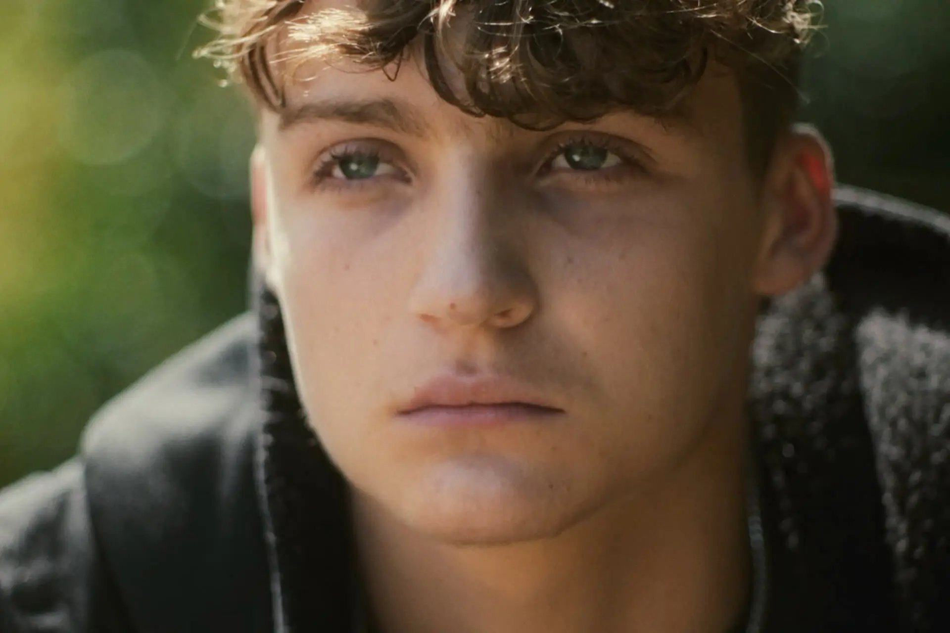 An upset man, Roman from the film Till Dawn, in a park, looking into the distance.