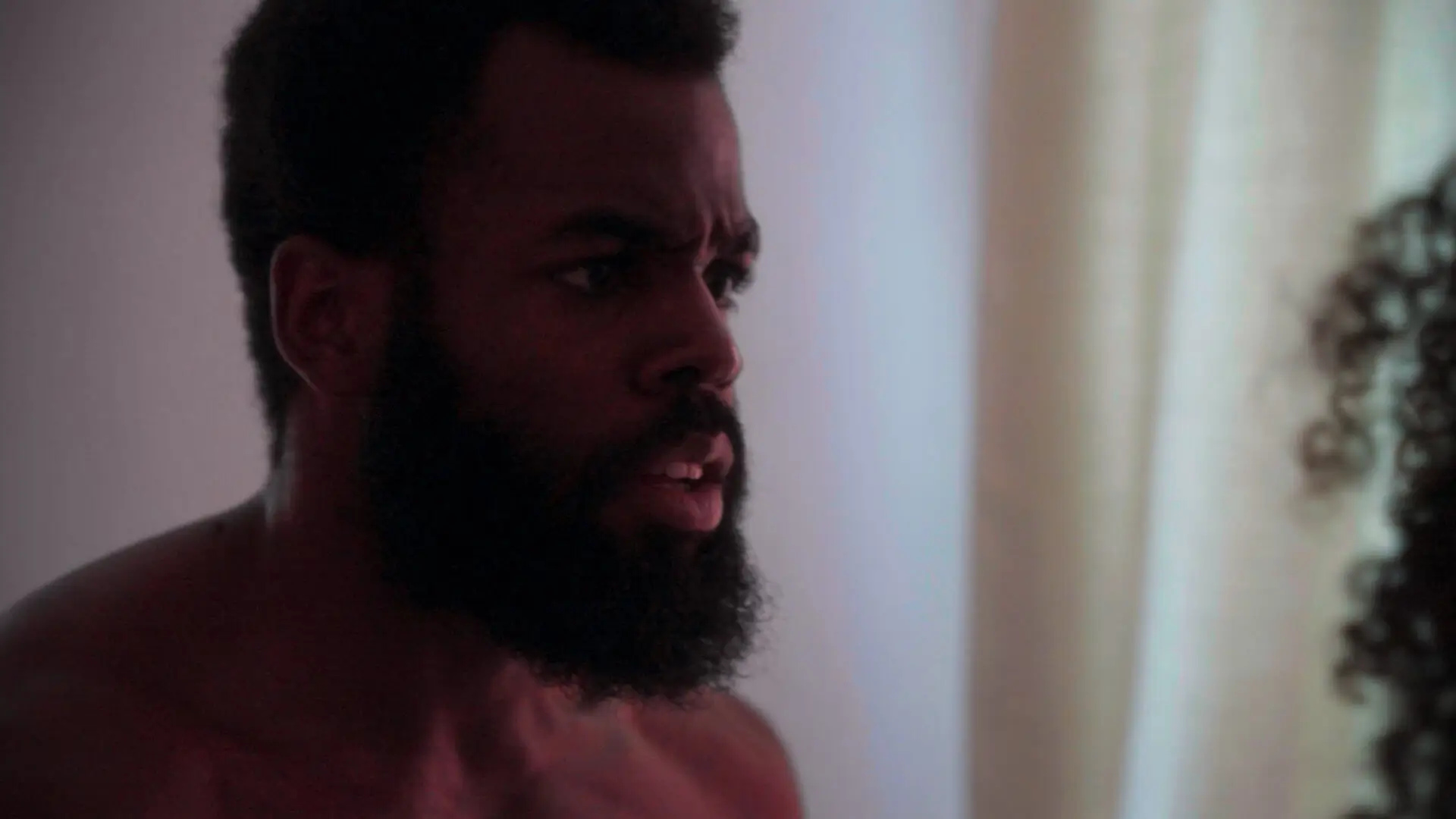An angry, topless man, Jason from the film Lesley, with a beard venting his frustration at a woman.