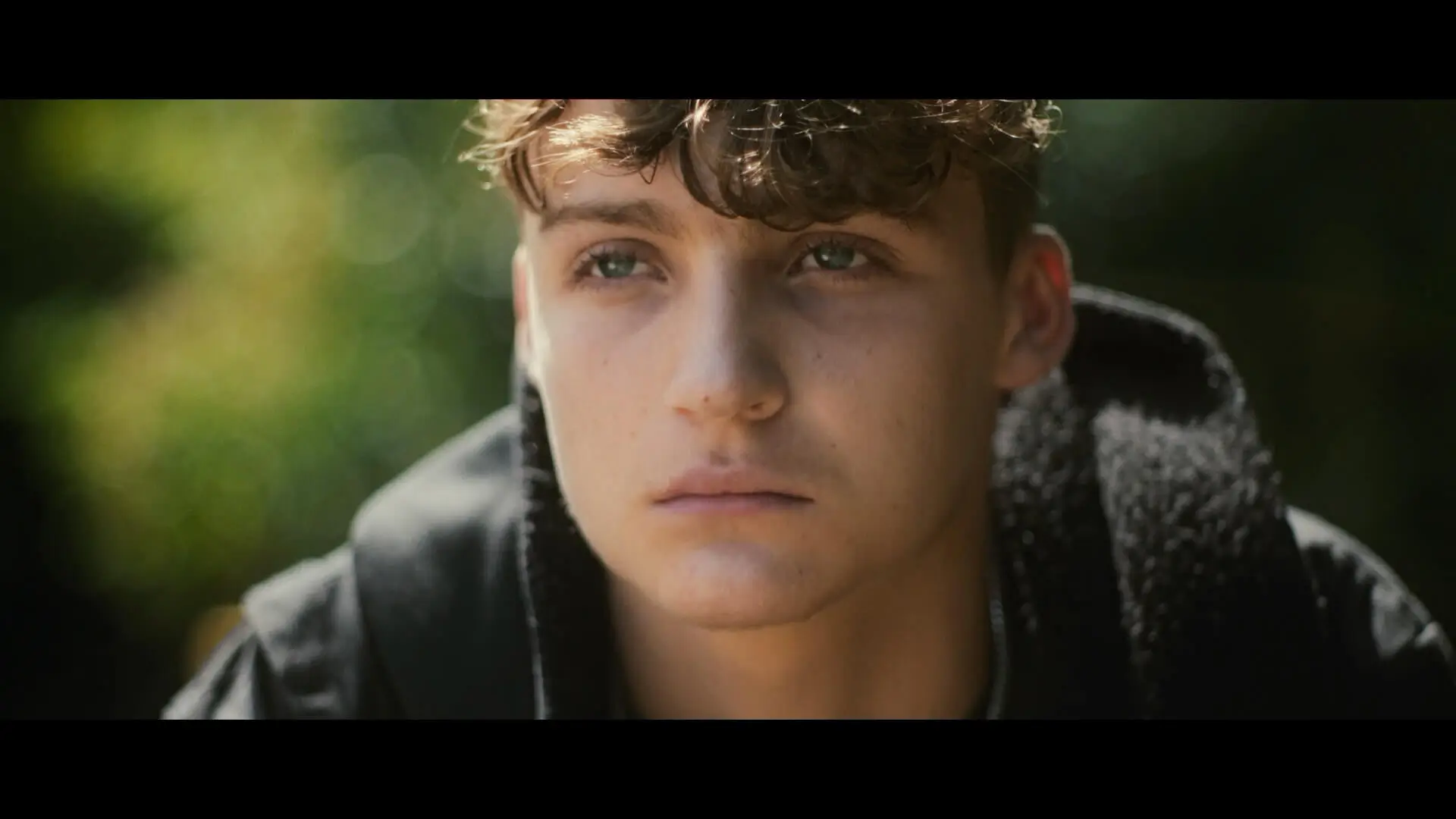 An upset man, Roman from the film Till Dawn, in a park, looking into the distance.