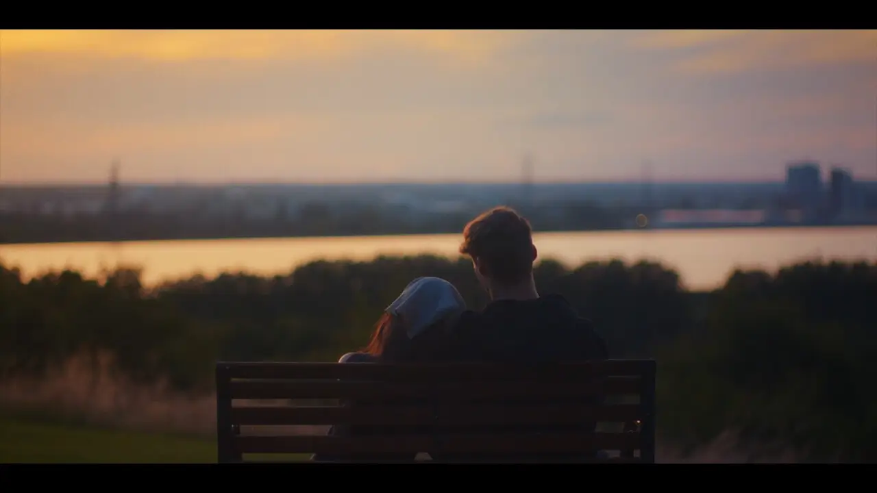 A man and woman sitting on a bench in the sunset with her head leaning on him - Till Dawn by MotionRay Pictures.